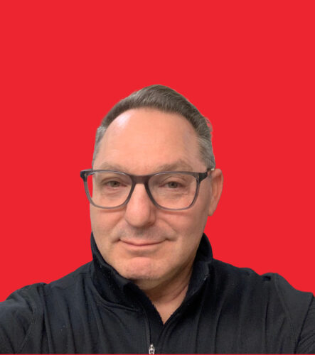 A man wearing glasses and a dark shirt is smiling at the camera. The red background features text: Instructor Spotlight: Norm Goldberg with contact details for First Aid Canada.